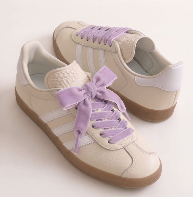 Lacets en velours lilas noués sur des baskets crème